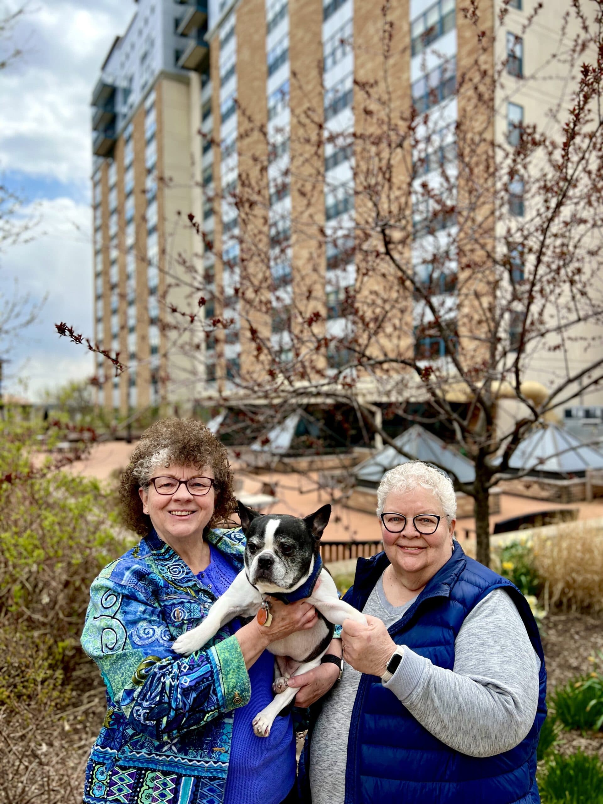 Catherine and Marty hold their dog outside of a Capitol Lakes residential building.
